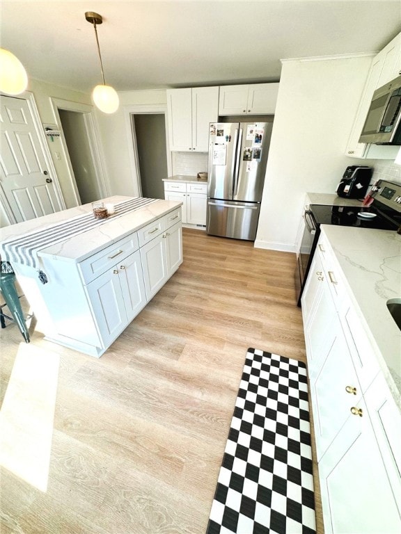 kitchen with light stone countertops, light wood-type flooring, white cabinetry, appliances with stainless steel finishes, and decorative light fixtures