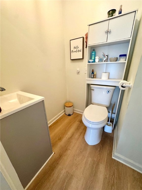 bathroom with toilet, baseboards, wood finished floors, and vanity