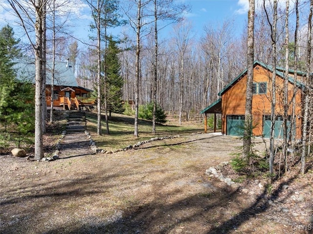 view of yard with dirt driveway and a forest view