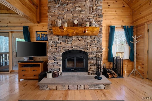 interior space with a stone fireplace, wood walls, and wood finished floors