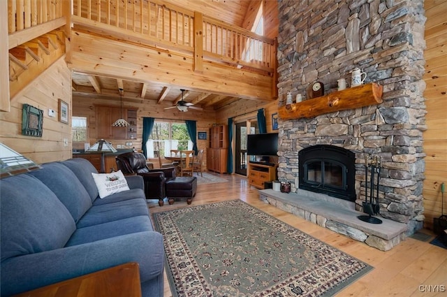 living area featuring wood-type flooring, a ceiling fan, wood walls, and wooden ceiling
