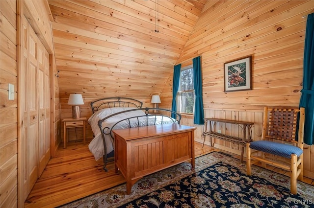 bedroom featuring wood walls, vaulted ceiling, and light wood-style flooring