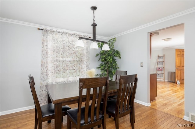 dining space with baseboards, ornamental molding, and light wood-style flooring