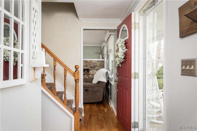 foyer entrance with ornamental molding, stairs, and wood finished floors