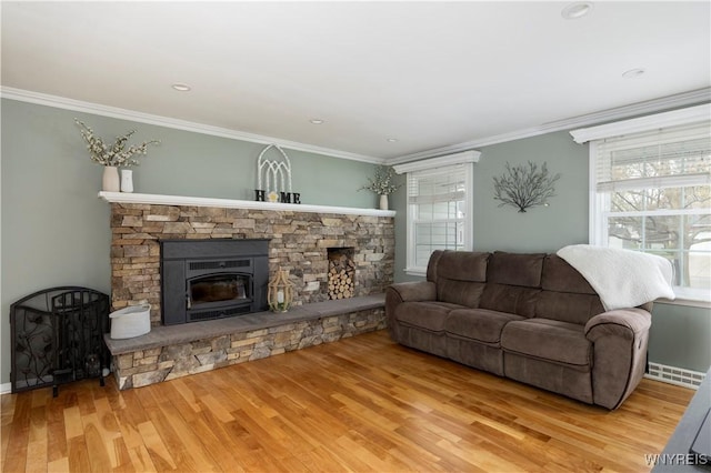 living area with baseboards, ornamental molding, a stone fireplace, and wood finished floors