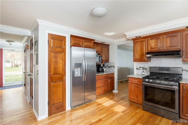 kitchen featuring under cabinet range hood, appliances with stainless steel finishes, light wood-style flooring, and tasteful backsplash