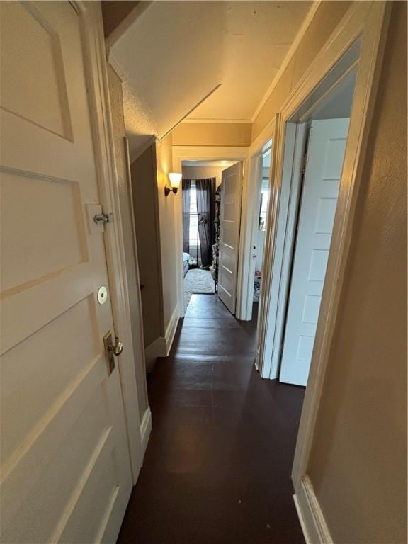 corridor featuring baseboards, ornamental molding, and dark wood-type flooring