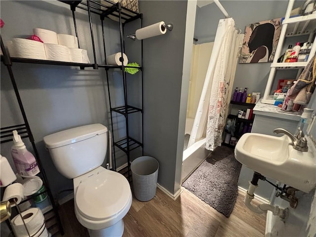 bathroom featuring baseboards, toilet, a shower with curtain, and wood finished floors