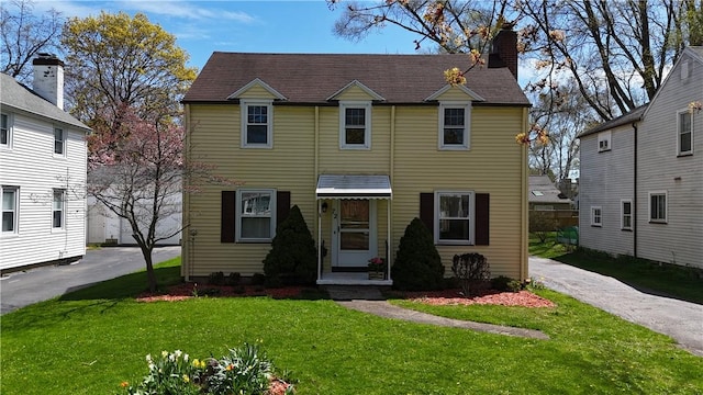 view of front of home with a chimney and a front yard