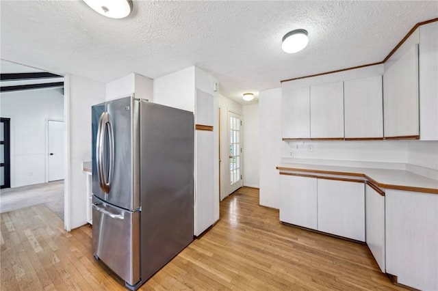 kitchen with freestanding refrigerator, light wood finished floors, and white cabinets