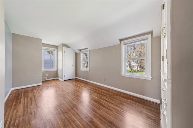 spare room with baseboards, visible vents, wood finished floors, and lofted ceiling