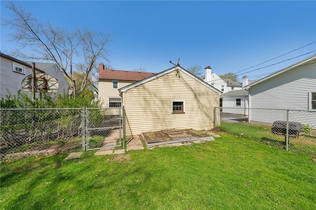 rear view of house with a lawn, a gate, and a fenced backyard
