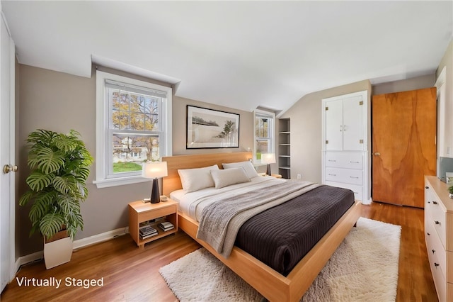 bedroom featuring baseboards, vaulted ceiling, and wood finished floors