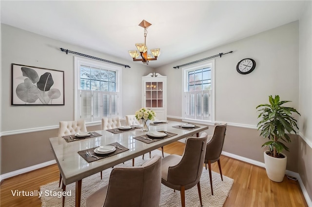dining room featuring baseboards, light wood finished floors, and a chandelier