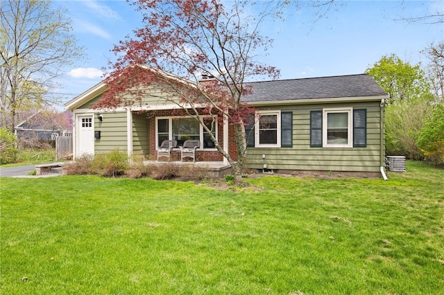 view of front of house with covered porch, a chimney, and a front yard