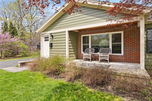 rear view of property with a yard and brick siding