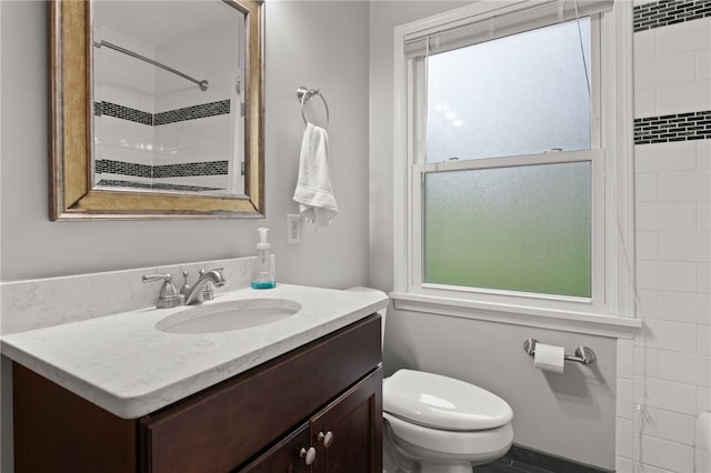 bathroom with vanity, a shower, a healthy amount of sunlight, and toilet