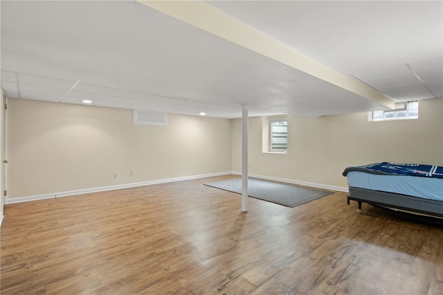 bedroom with baseboards, multiple windows, and wood finished floors