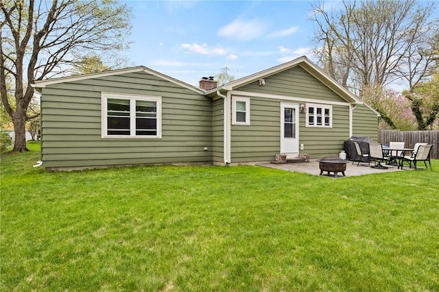 back of property featuring a chimney, a yard, a fire pit, and a patio area
