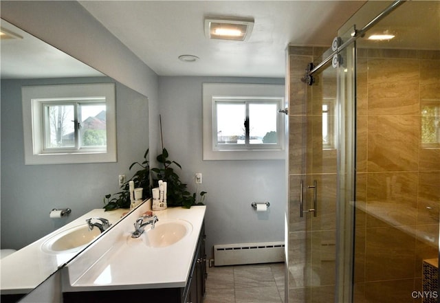 bathroom with double vanity, a baseboard heating unit, a sink, and a stall shower