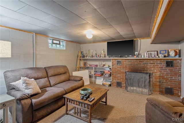 living area featuring concrete block wall, carpet, and a brick fireplace