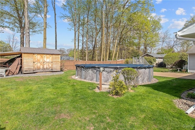 view of yard featuring fence, a fenced in pool, an outbuilding, and a shed