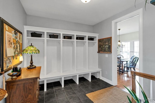 mudroom featuring dark tile patterned floors, baseboards, and a notable chandelier