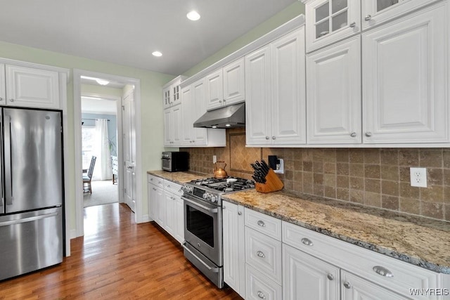 kitchen featuring wood finished floors, white cabinetry, appliances with stainless steel finishes, and under cabinet range hood