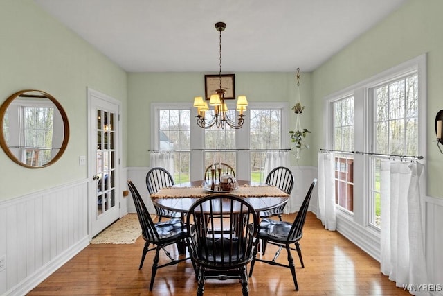dining area featuring a notable chandelier, wainscoting, and wood finished floors