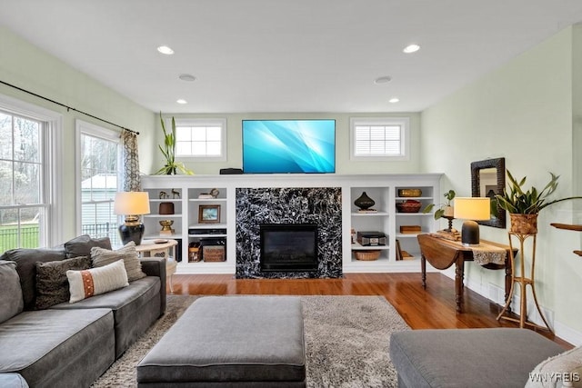 living area featuring a healthy amount of sunlight, a fireplace, recessed lighting, and wood finished floors