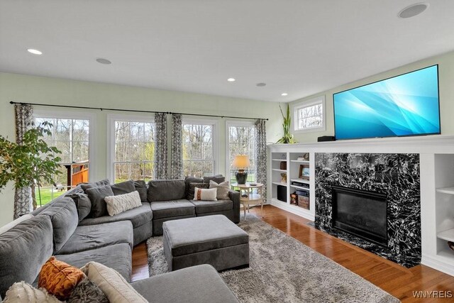 living area with recessed lighting, wood finished floors, and a high end fireplace