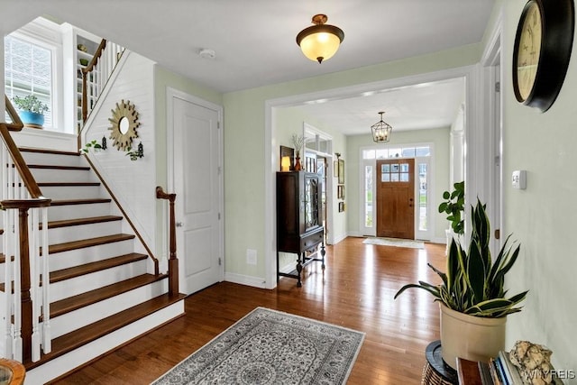 entryway featuring stairs, baseboards, an inviting chandelier, and wood finished floors
