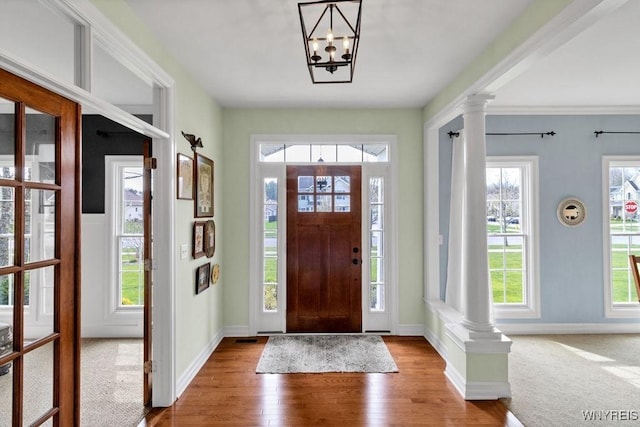 foyer entrance with an inviting chandelier, baseboards, decorative columns, and wood finished floors