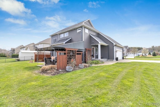 rear view of house featuring a lawn, a garage, fence, and concrete driveway