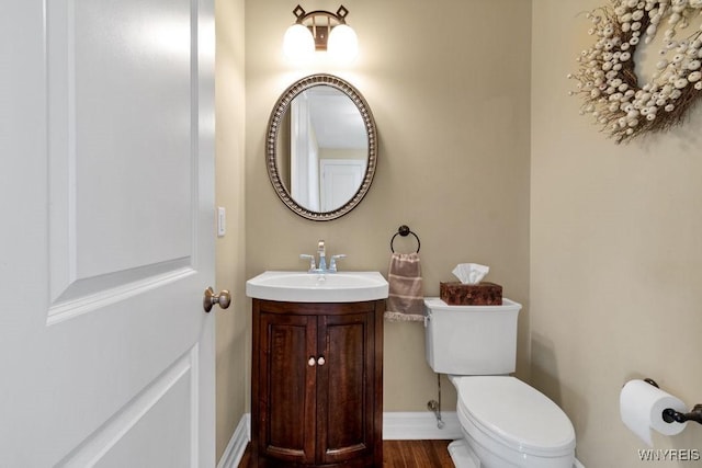bathroom with toilet, baseboards, wood finished floors, and vanity