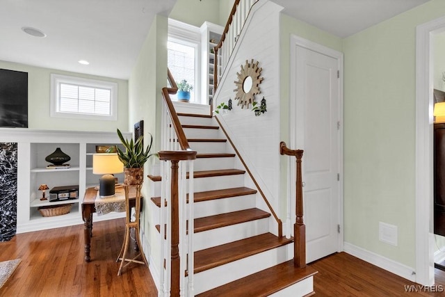 stairway featuring baseboards, recessed lighting, built in features, and wood finished floors