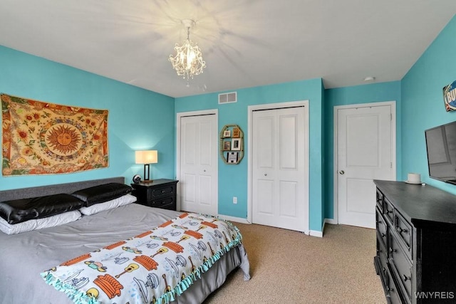 bedroom featuring visible vents, baseboards, two closets, an inviting chandelier, and carpet