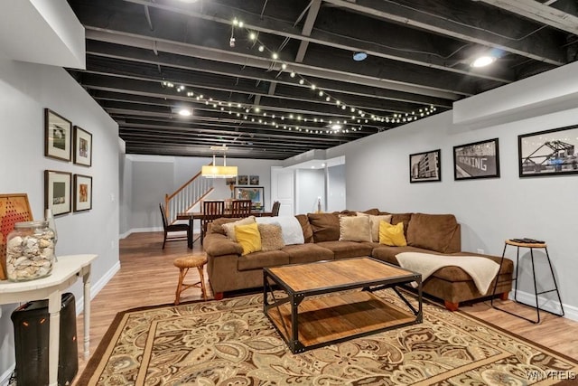 living area featuring baseboards, light wood-style flooring, and stairway