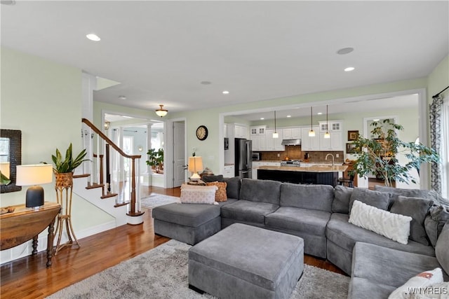 living area featuring recessed lighting, dark wood finished floors, and stairs