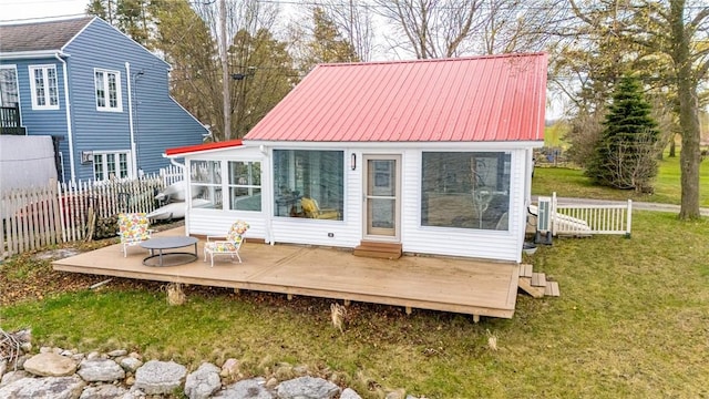 rear view of house with fence, a wooden deck, a sunroom, and metal roof