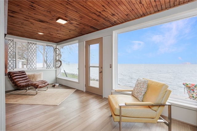 sunroom / solarium with a water view, wood ceiling, and wood finished floors