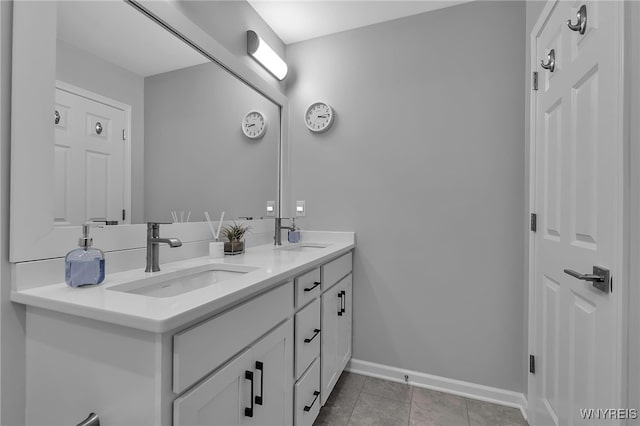 full bathroom with a sink, baseboards, tile patterned floors, and double vanity