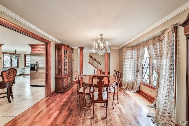 dining area featuring crown molding, decorative columns, baseboards, a chandelier, and light wood-style flooring