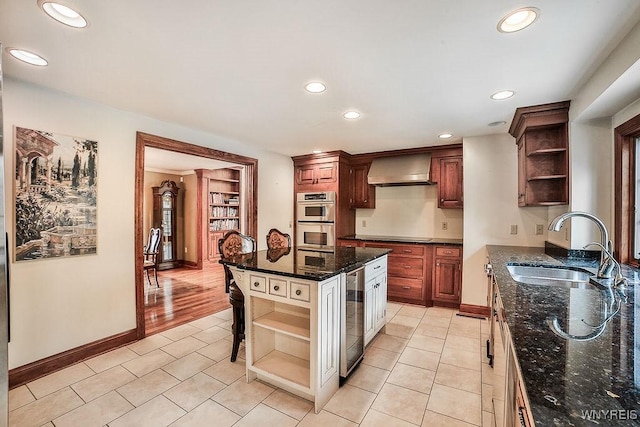 kitchen with stainless steel double oven, open shelves, a sink, wine cooler, and wall chimney exhaust hood