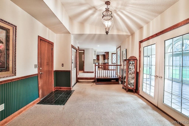 carpeted entryway featuring a wainscoted wall and french doors