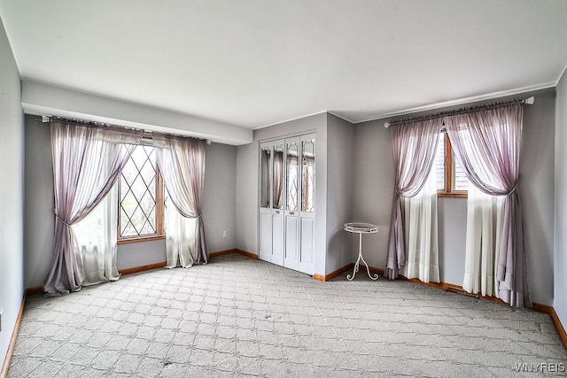 spare room featuring baseboards and light colored carpet