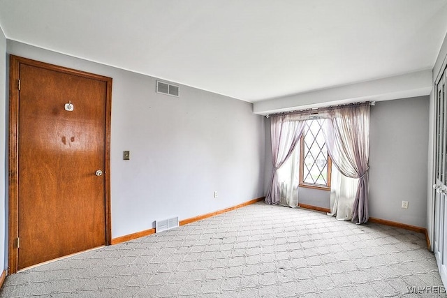 unfurnished room with baseboards, light colored carpet, and visible vents