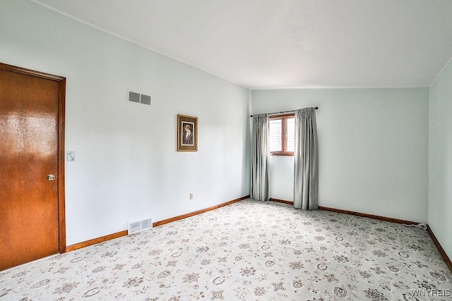 spare room featuring baseboards, vaulted ceiling, and visible vents