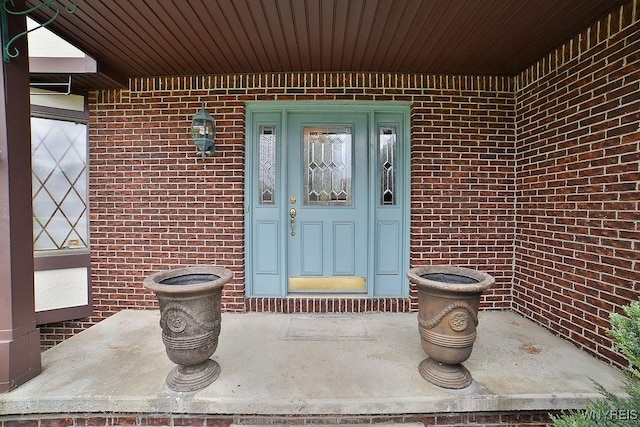 property entrance featuring brick siding and a porch