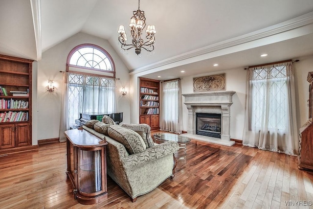 living room featuring baseboards, a fireplace with raised hearth, an inviting chandelier, recessed lighting, and hardwood / wood-style floors